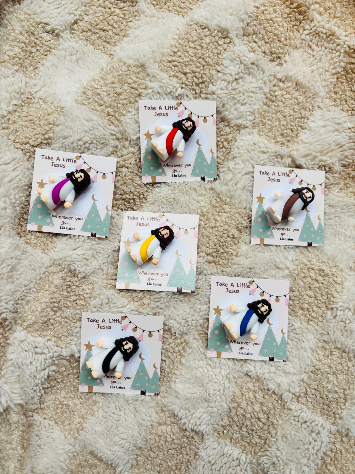 6 mini Jesus firgurines on a Christmas backing card resting on a cream blanket