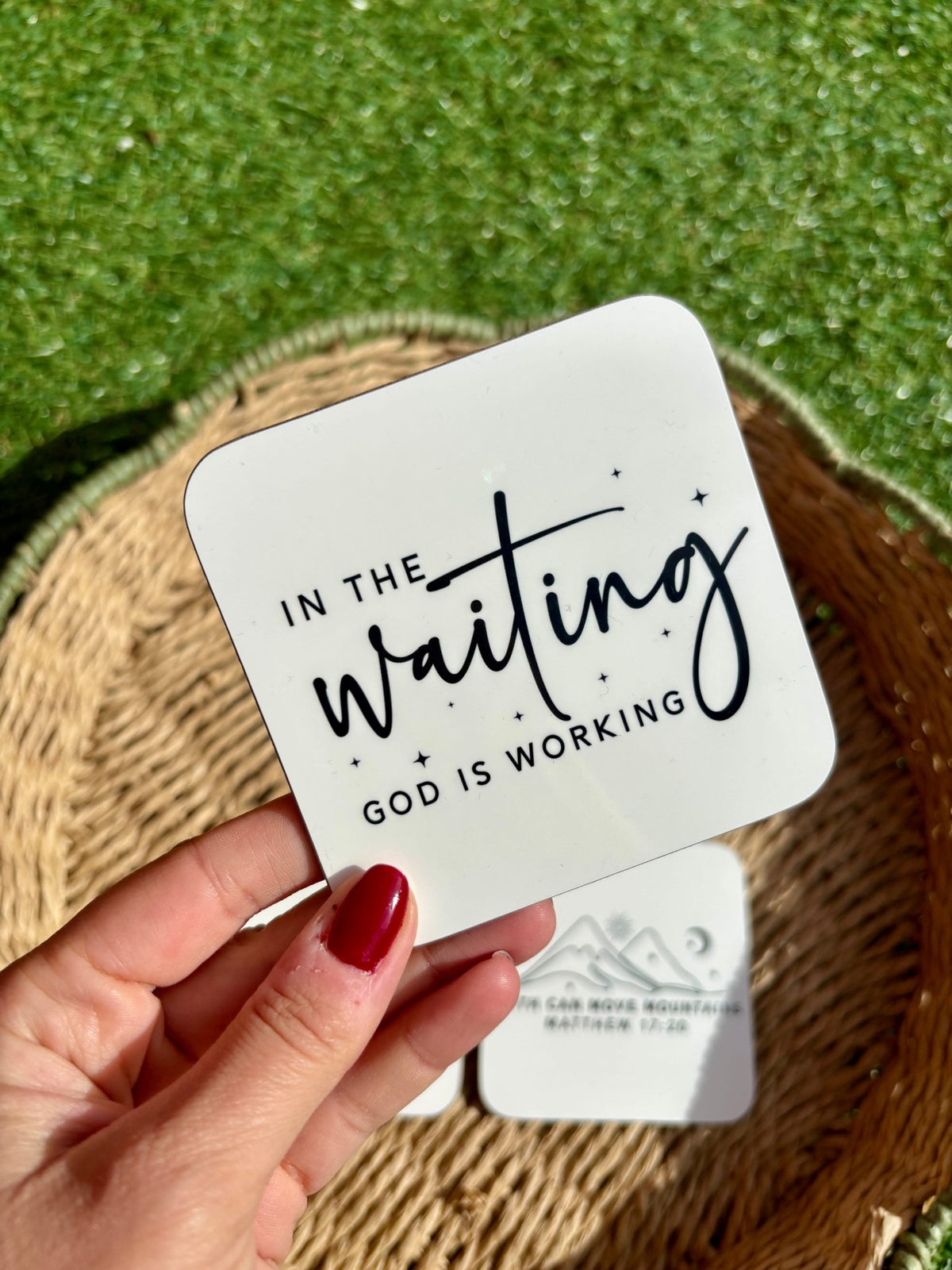 'In the waiting, God is working' quote printed in black text on a white coaster with a hardboard backing