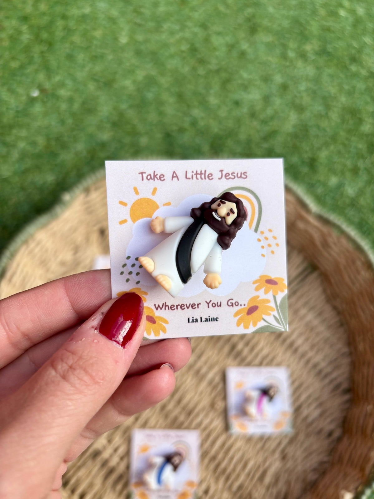 Jesus Pocket Card, black mini Jesus figurine on a sun and rainbow backing card with other colours and grass in the background.