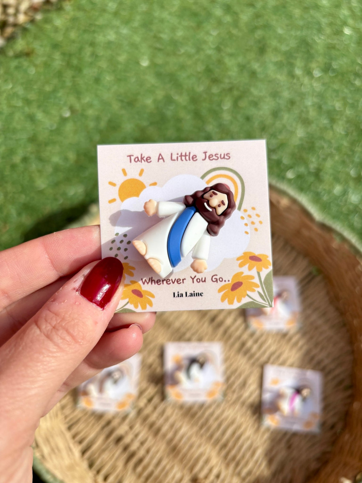 Jesus Pocket Card, blue mini Jesus figurine on a sun and rainbow backing card with other colours and grass in the background.